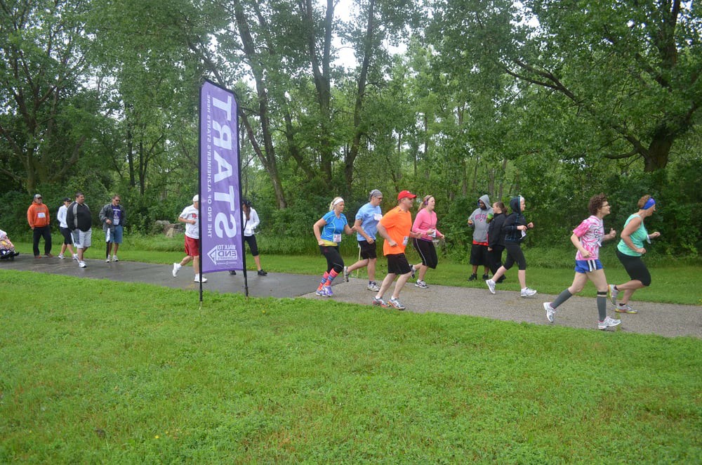 Runners taking off from the start line in a park race event.