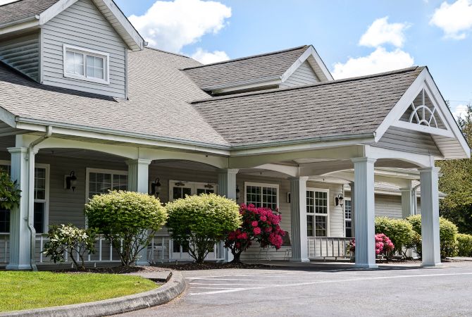 A house with a landscaped entrance featuring shrubs and flowering plants.