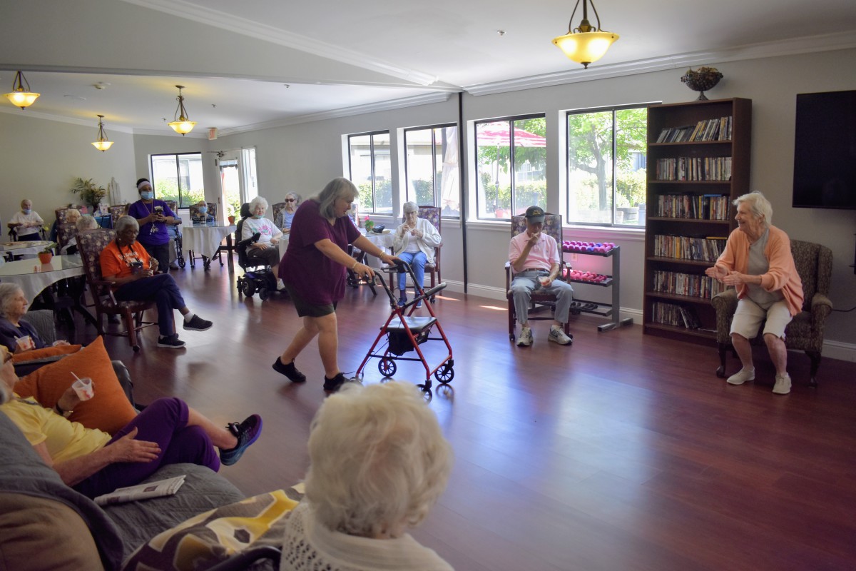 Residents gather in a community room at an assisted living facility, engaging in social activities.
