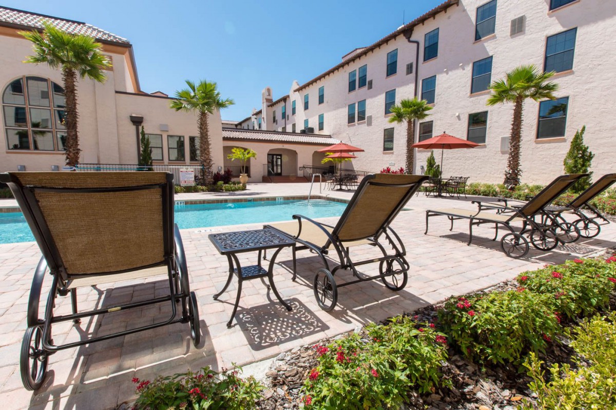 A sunny, outdoor pool area with lounge chairs and patio furniture.
