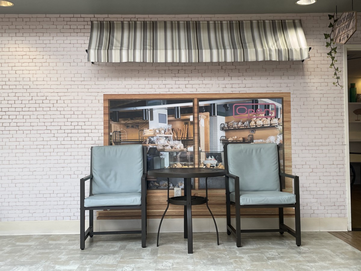 Outdoor seating arrangement with two chairs and a table in front of a cafe storefront.