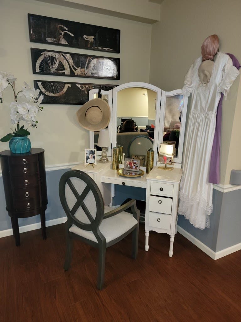 A vintage-style vanity setup with a mirror, chair, and elegant decor.