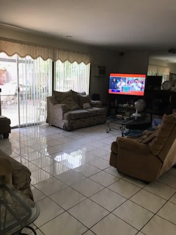 A cozy living room with sofas and a television, featuring glass doors leading outside.
