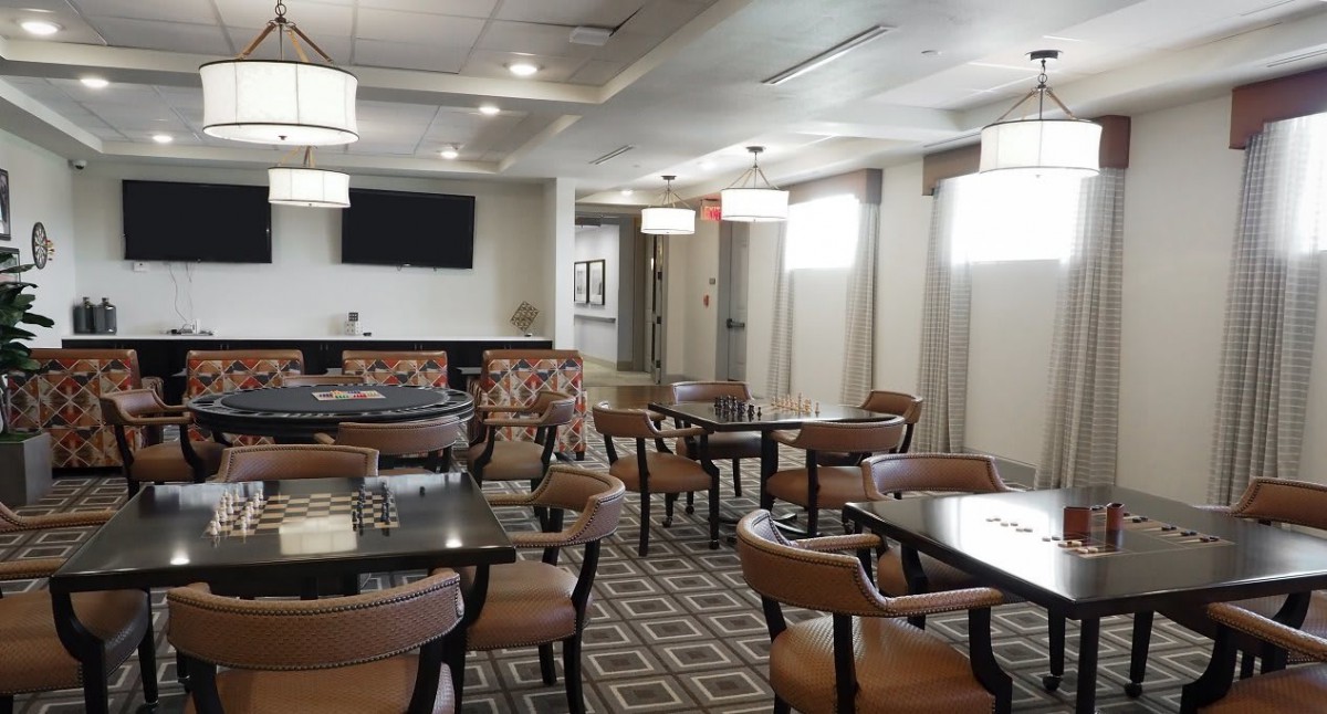 An empty dining area with neatly arranged tables and chairs, featuring modern lighting.