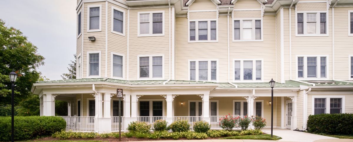 A three-story residential building with a porch and well-maintained landscaping.
