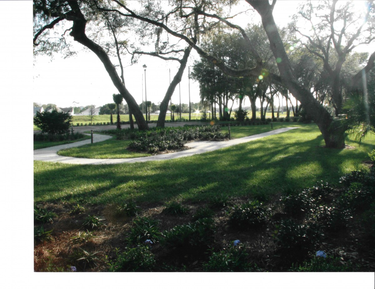 A scenic outdoor park with a winding pathway surrounded by trees and grass.