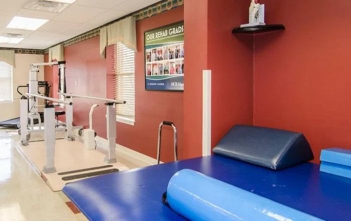 A rehabilitation room equipped with exercise equipment and a therapy mat.