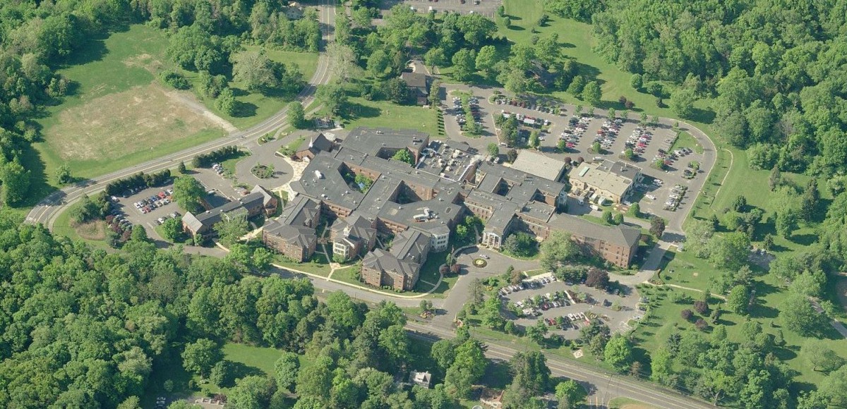 Aerial view of a building complex surrounded by trees and parking areas.