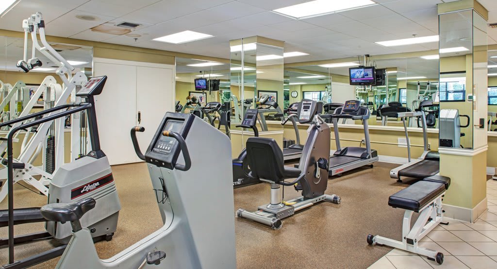 A gym equipped with treadmills and other exercise machines, surrounded by mirrors.