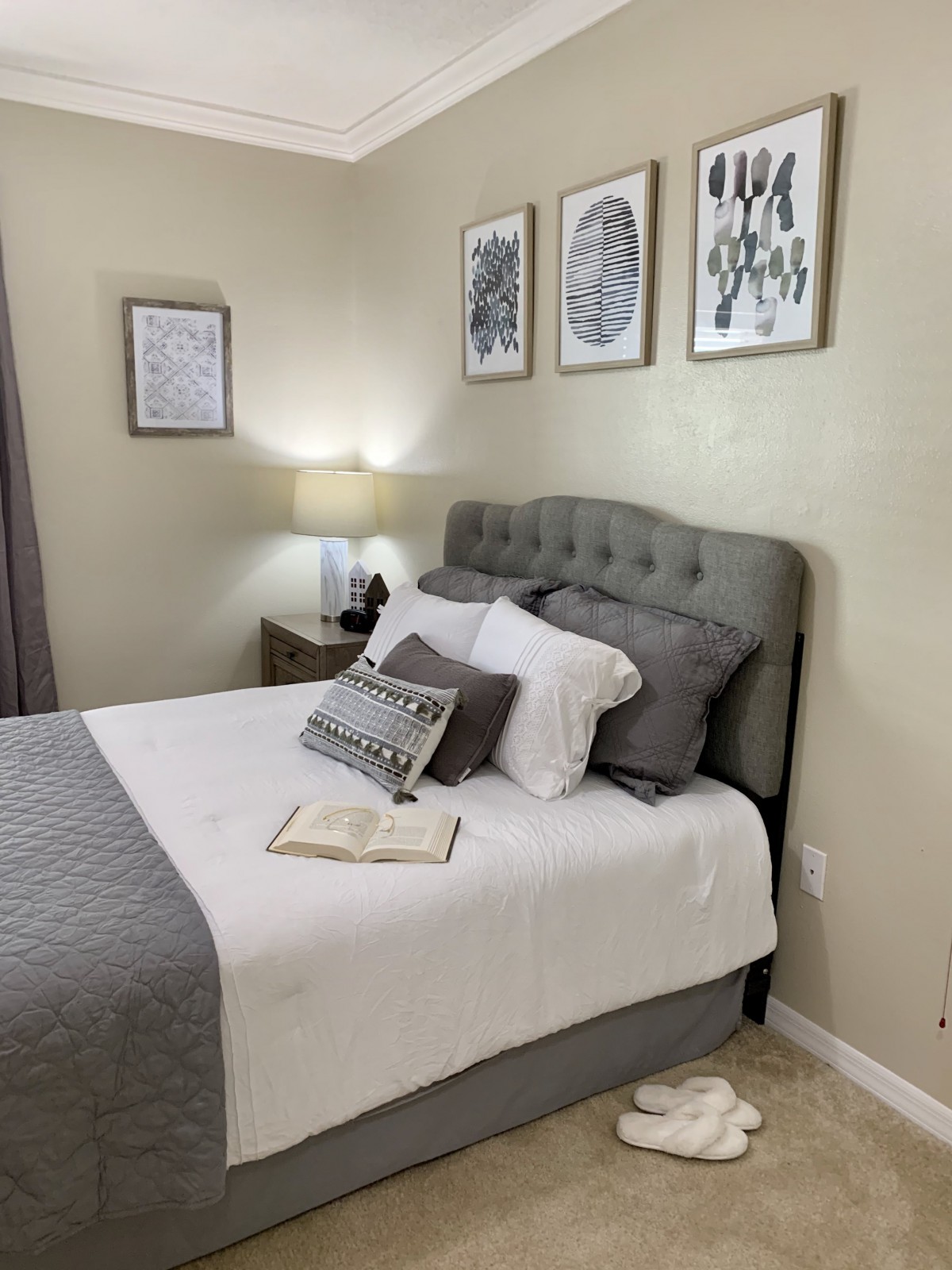 A cozy bedroom with a neatly made bed, decorative pillows, and framed artwork on the wall.