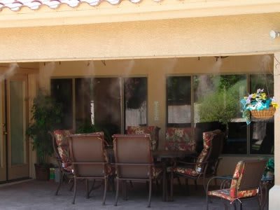 Outdoor patio with a set of chairs and a table under mist cooling system.