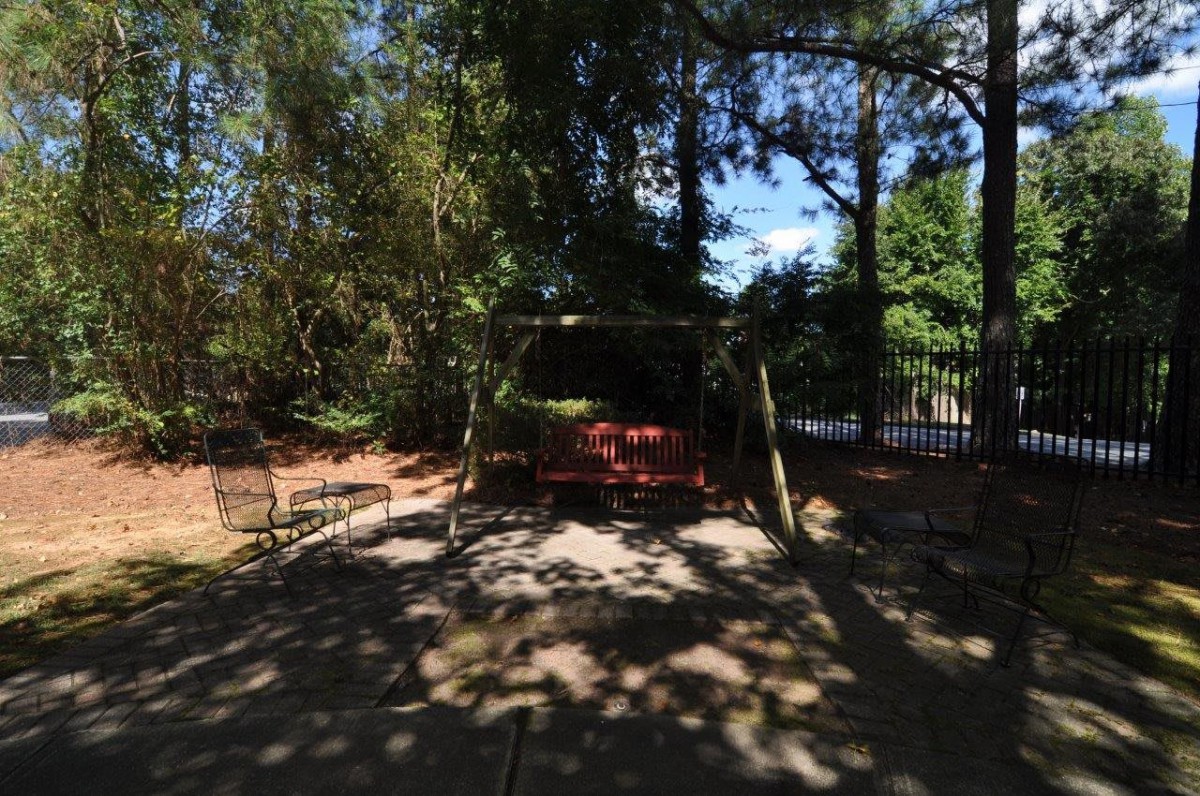 A shaded garden area with a swing surrounded by trees.