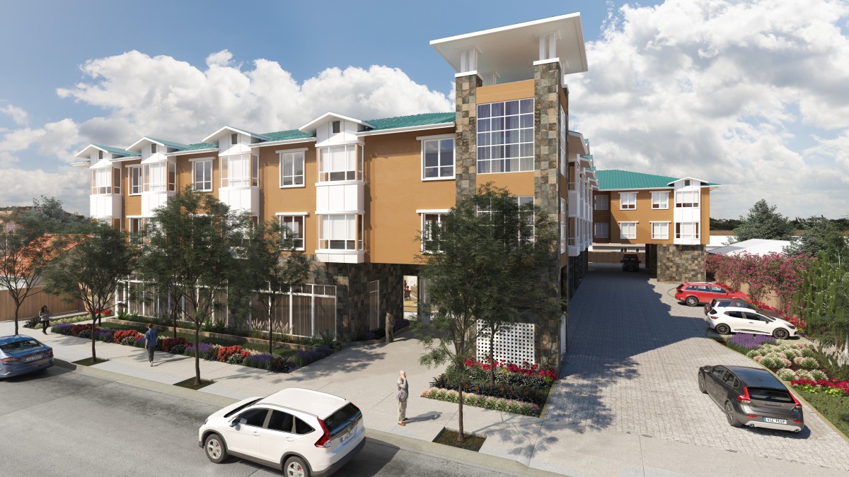 A modern apartment building with a parking area and surrounding trees under a clear sky.