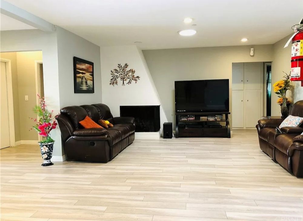 A modern living room featuring a comfortable sofa, large television, and a fireplace with stylish decor.
