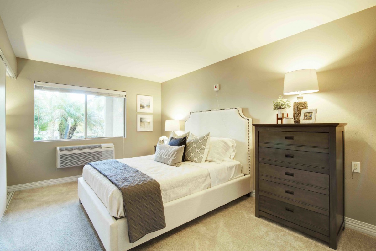A modern bedroom with a comfortable bed, stylish dresser, and soft lighting.