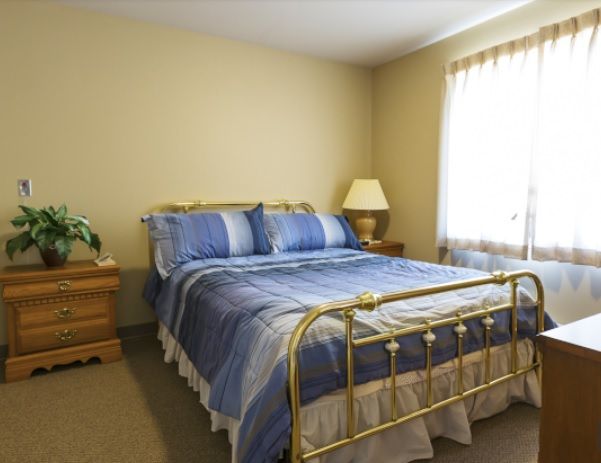 A cozy bedroom with a brass bed frame and blue bedding.