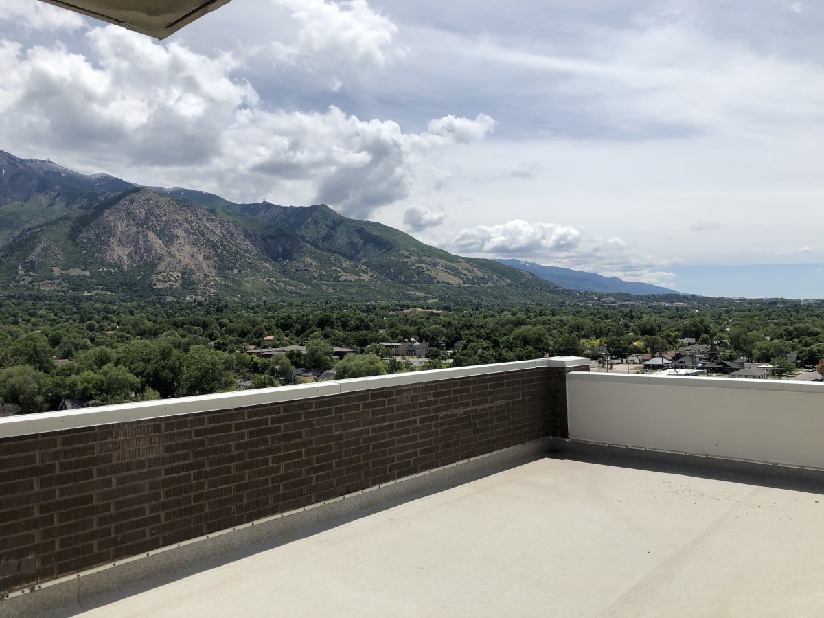 A scenic mountain view from a balcony under a partly cloudy sky.