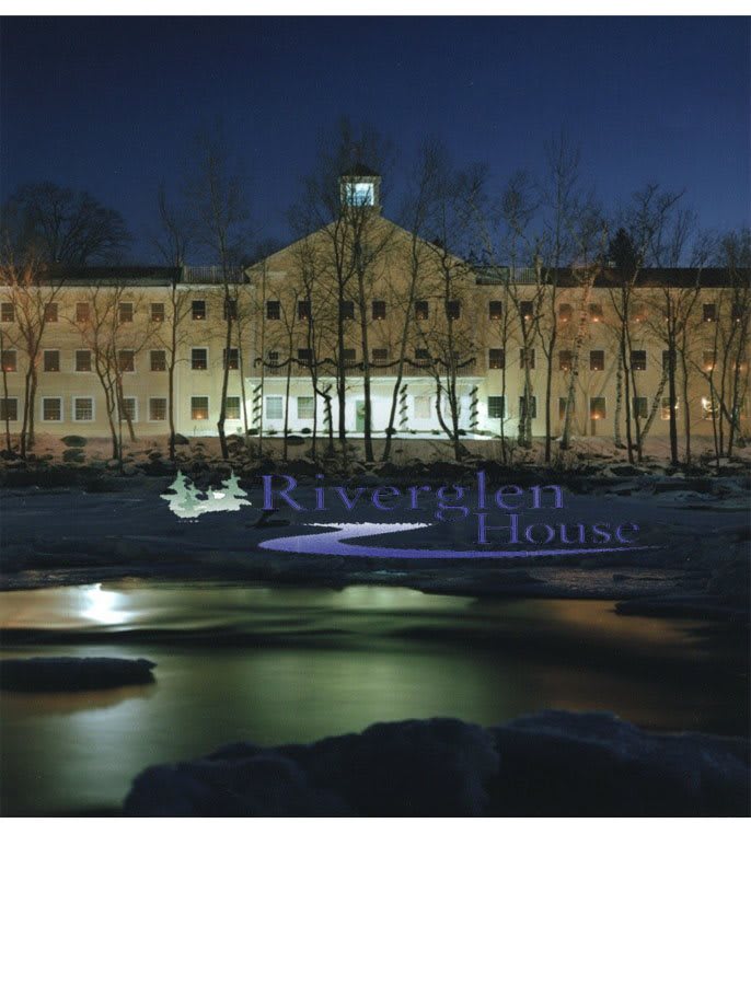 A riverside building illuminated at night with reflections on the water.