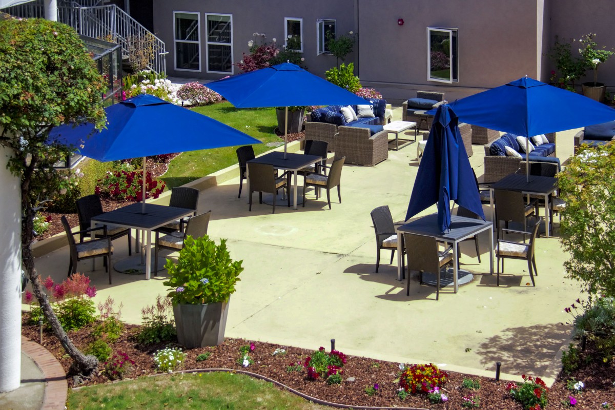 A cozy outdoor patio area with blue umbrellas and comfortable seating.