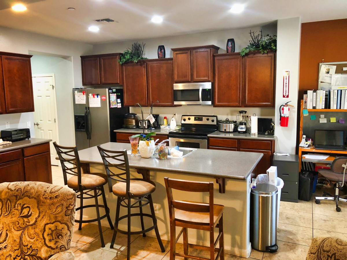 A modern kitchen with wooden cabinets, a spacious countertop, and chairs around a central island.