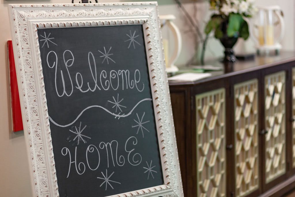 A decorative chalkboard sign reading 'Welcome Home' in a cozy interior setting.