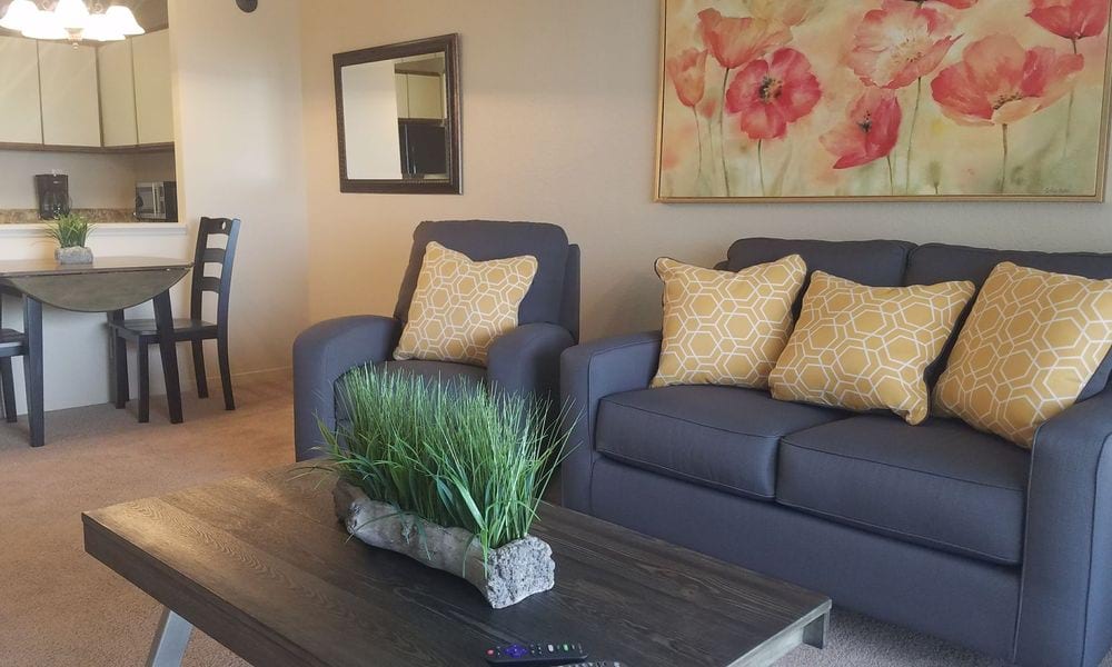 A cozy living room with a sofa set, decorative cushions, and wall art.