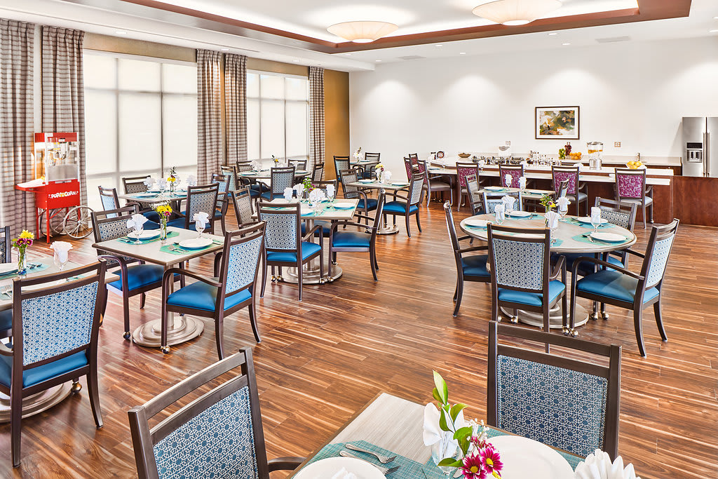 A well-lit dining area with neatly arranged tables and chairs, featuring a wooden floor and elegant decor.