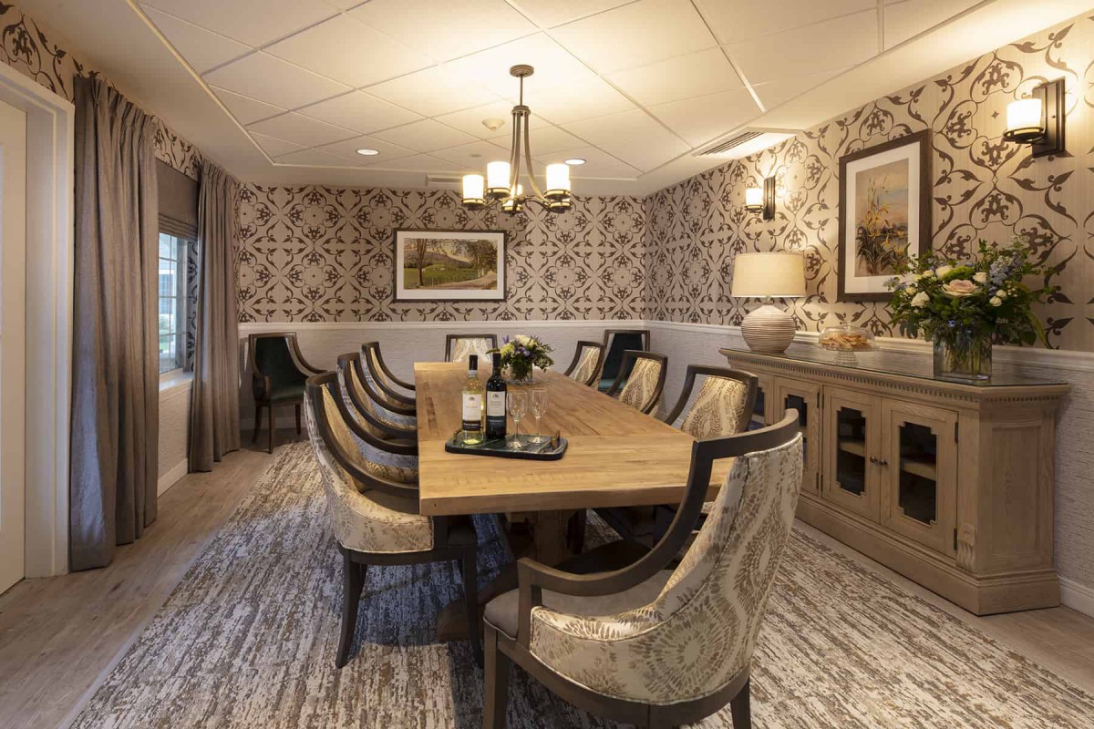 Elegant dining room with a long wooden table, upholstered chairs, and stylish wallpaper.