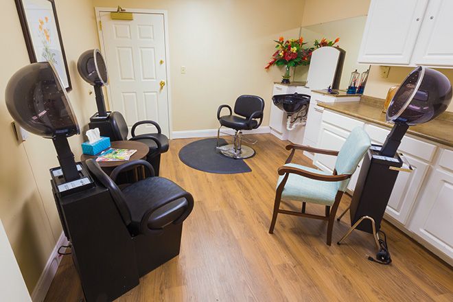 A cozy hair salon interior with chairs and a mirror, adorned with flowers.