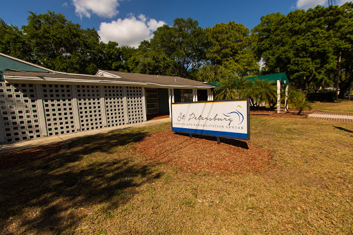 A view of a building with a prominent sign, surrounded by grassy areas and trees.