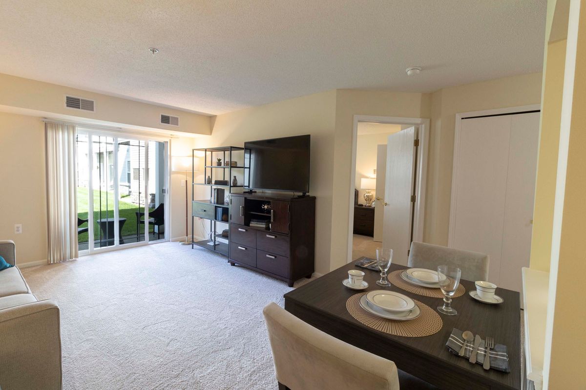 A modern apartment interior featuring a cozy living room with a TV and an adjacent dining area.
