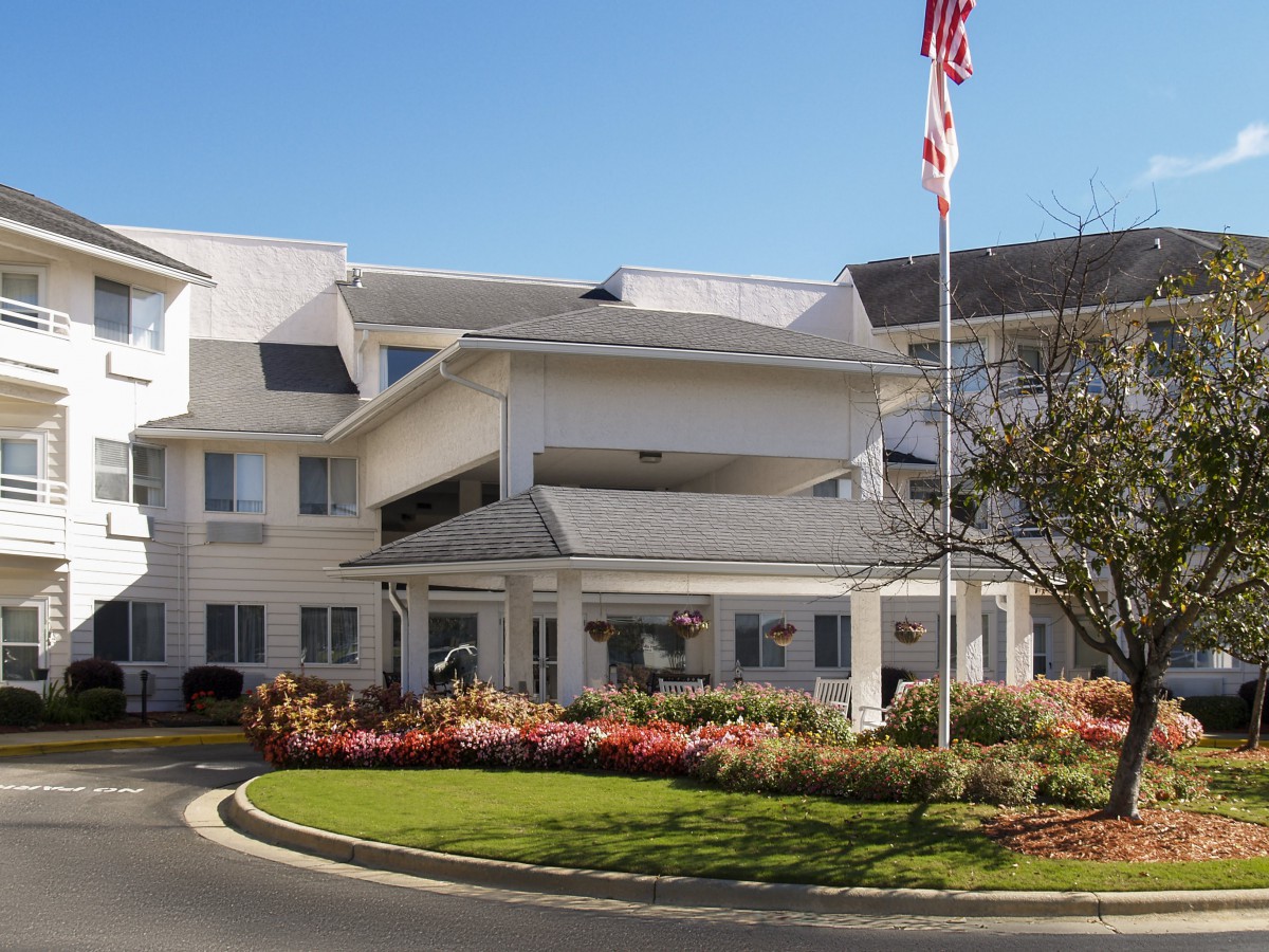 Entrance to a well-maintained building with landscaped surroundings and an American flag.