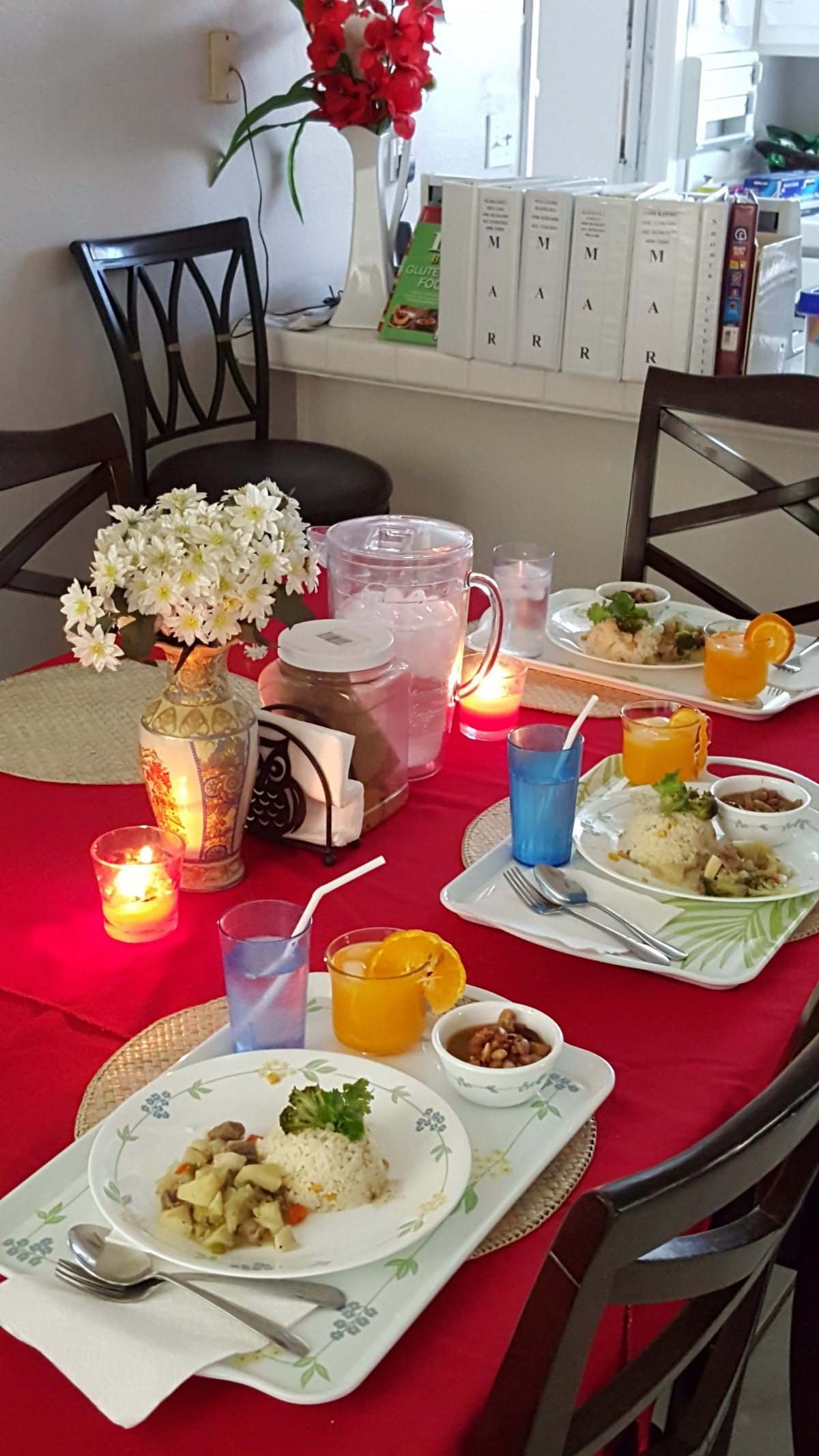 A beautifully set dining table with candles, flowers, and meals ready to be enjoyed.