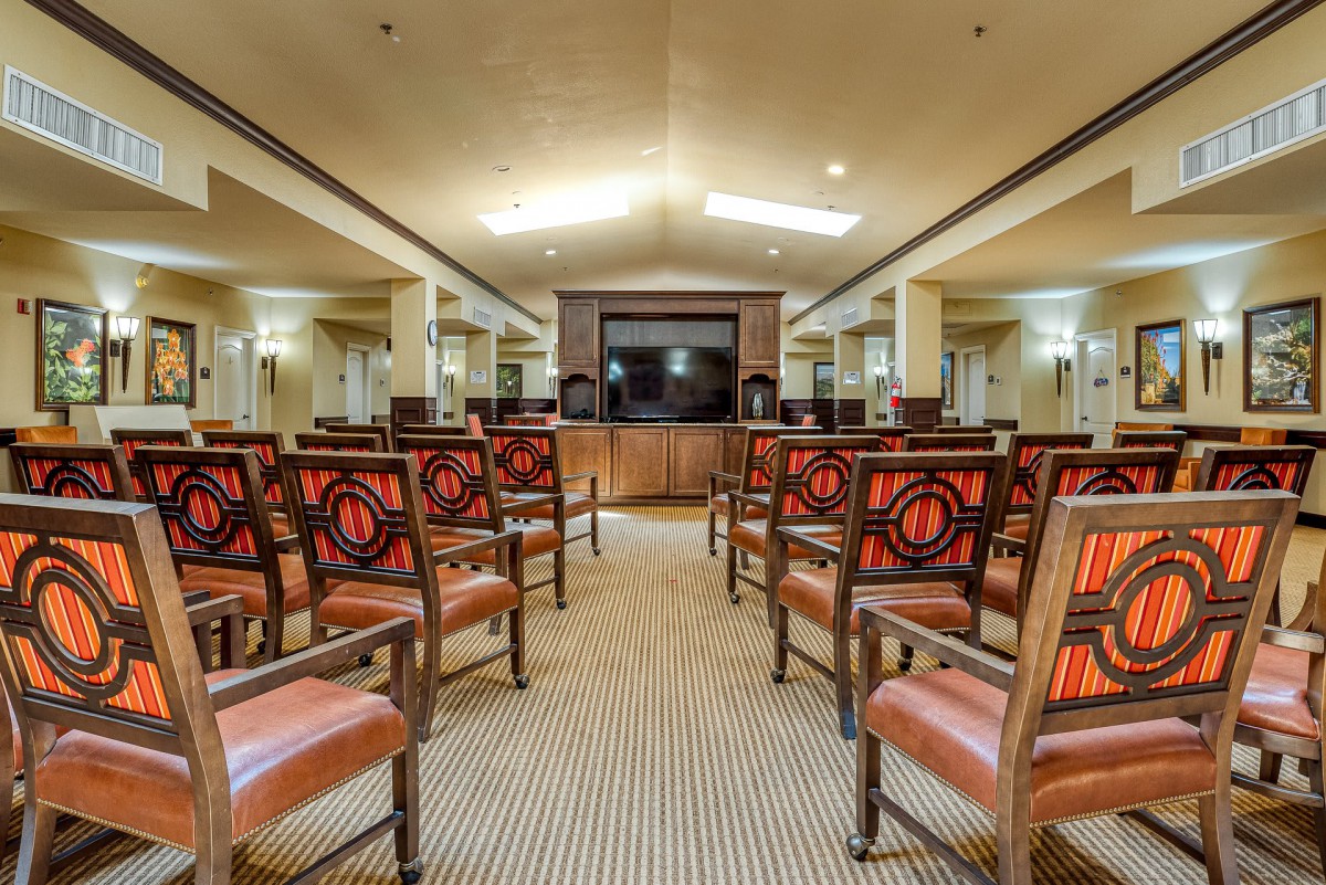 An empty meeting room with rows of chairs facing a central stage.