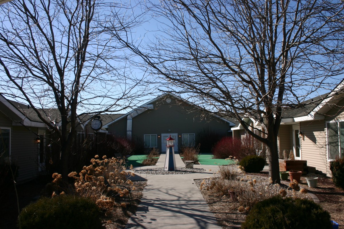 A building surrounded by bare trees and a landscaped path on a sunny winter day.