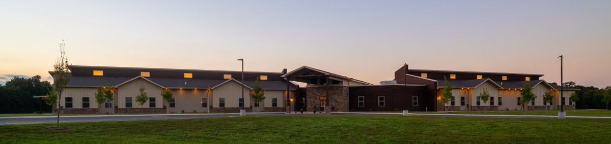 A modern building exterior at sunset with a grassy foreground.
