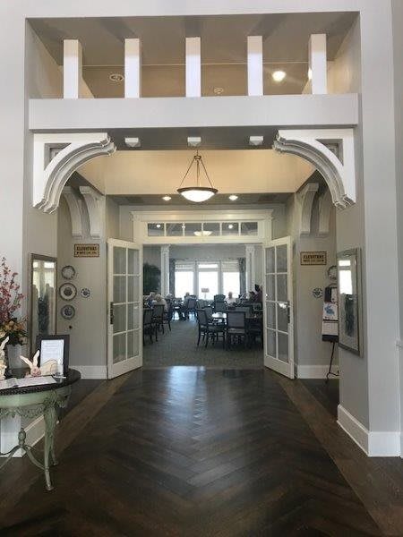 A spacious entrance with double doors and a chandelier leads into a well-lit room.