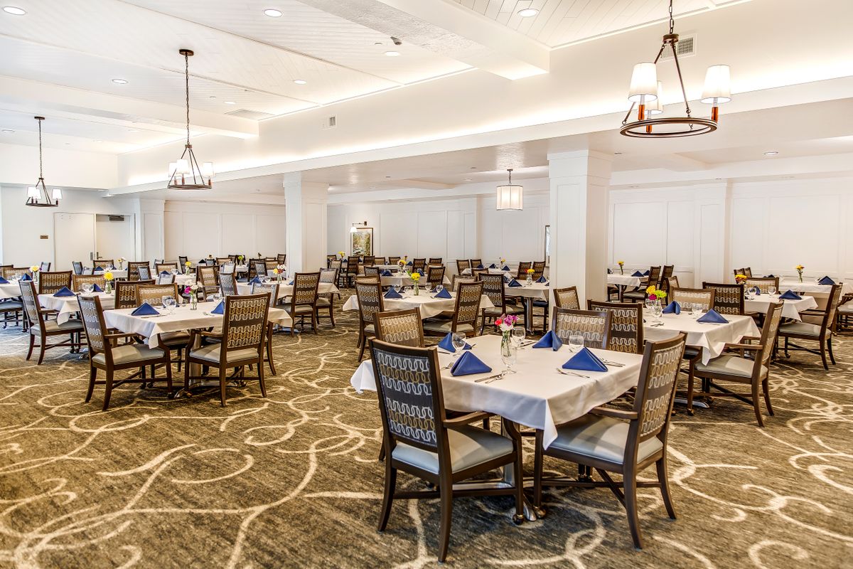 A spacious and elegantly decorated dining room with several tables set for a meal.