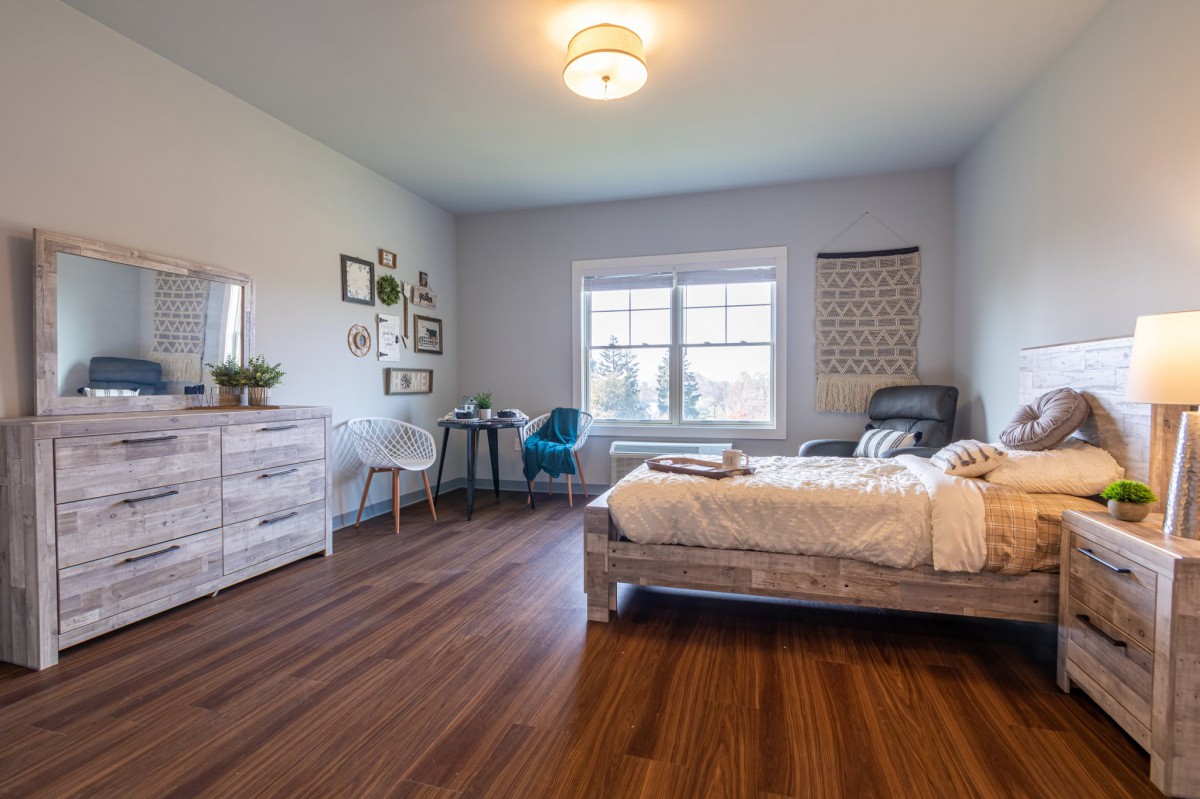 A cozy bedroom with modern decor, featuring a bed, desk, and ample natural light.