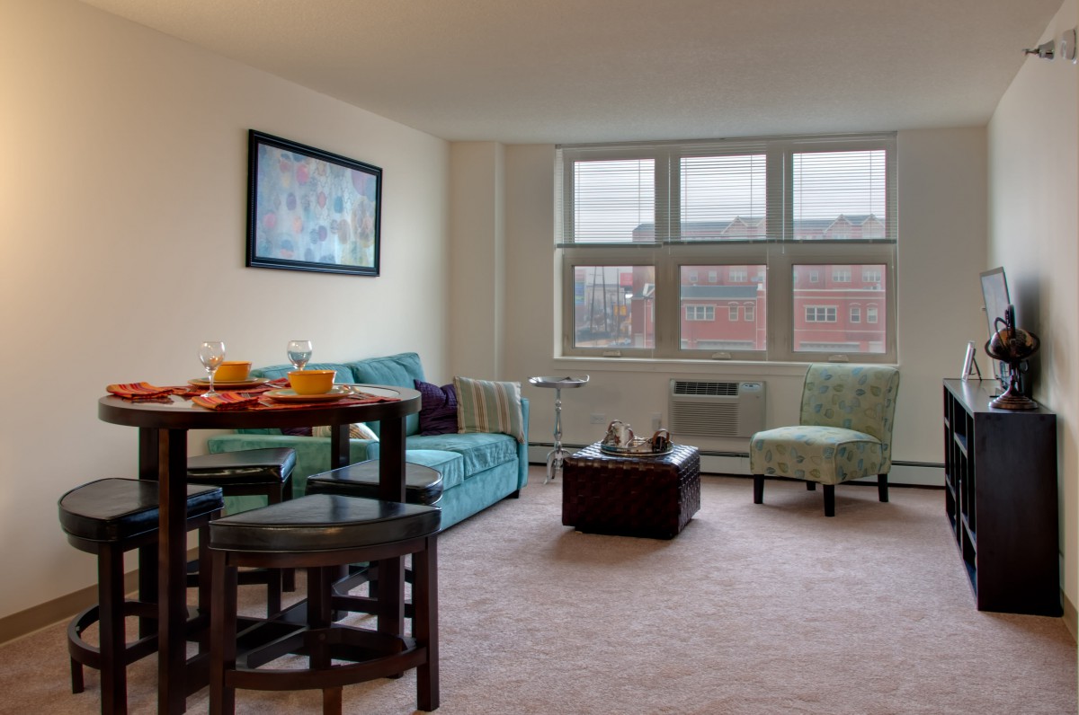 A cozy living room with a comfortable couch, dining table, and large windows.