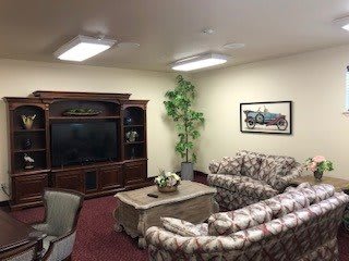 A cozy living room featuring a large TV, patterned sofas, and a coffee table.