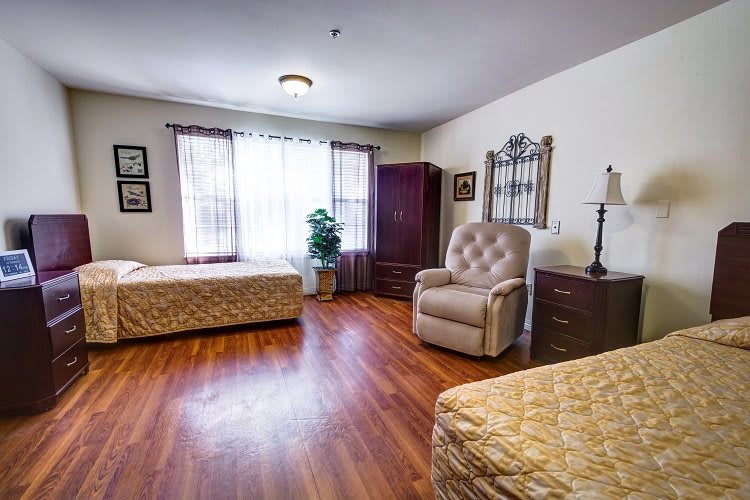 A cozy bedroom with two beds, an armchair, and a wardrobe.