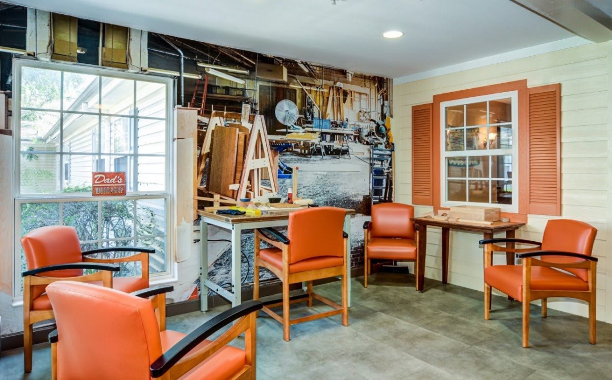A cozy indoor workshop with orange chairs and a wall featuring various tools.