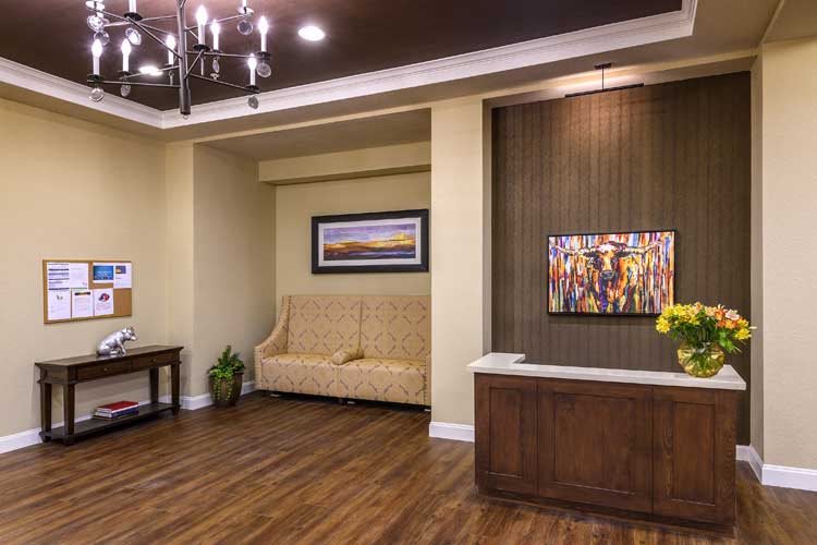 A modern reception area featuring a comfortable sofa, wooden flooring, and decorative artwork on the walls.