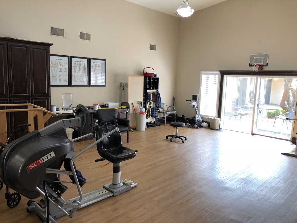 A spacious room with salon chairs and exercise equipment on a wooden floor.