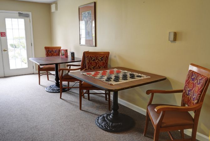 A cozy game room featuring a checkers board on a table with comfortable chairs.