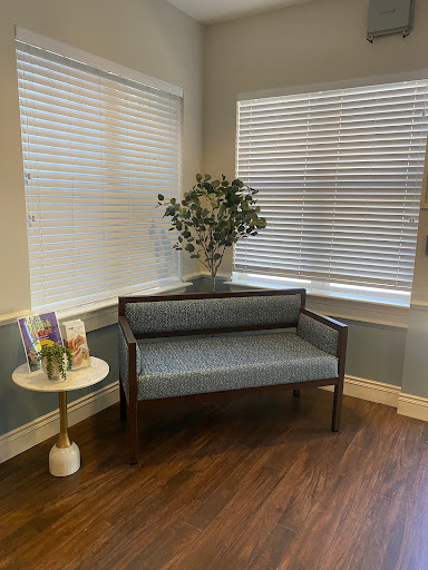 A cozy corner featuring a stylish bench, a decorative plant, and softly lit windows.