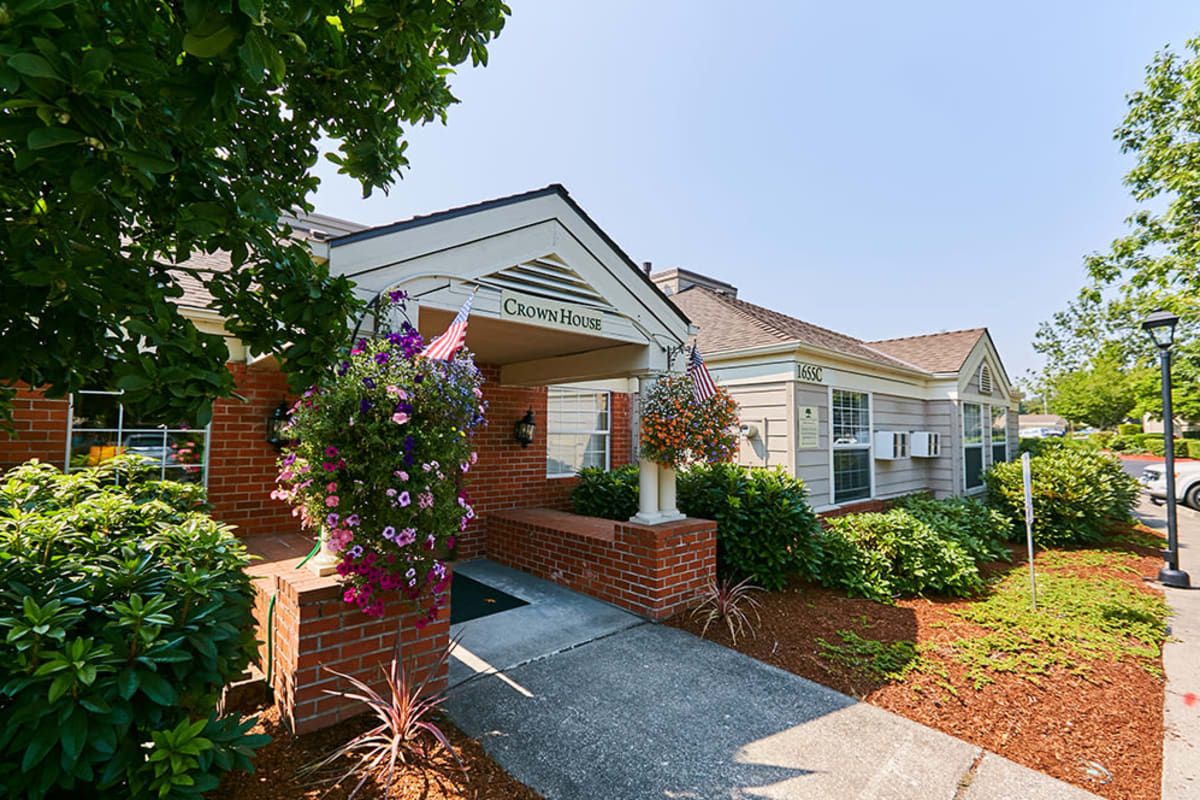 A charming building entrance adorned with floral arrangements and well-maintained landscaping.