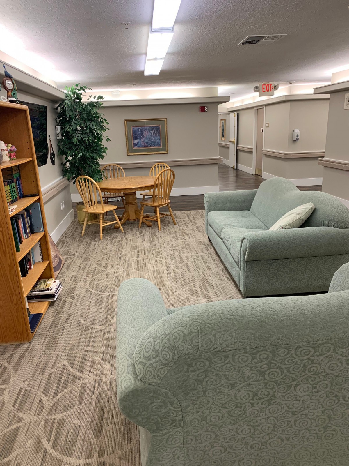 A cozy common area with seating, bookshelves, and a dining table.