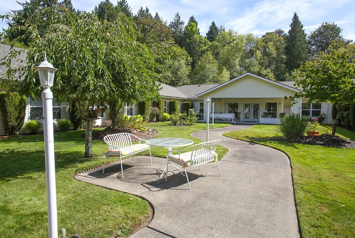 A charming house with a well-maintained garden and patio furniture along a curved pathway.